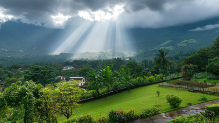 A breathtaking landscape featuring sun rays breaking through dark clouds over lush greenery and distant mountains. A tranquil view perfect for nature lovers.の素材