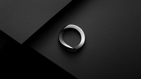 This striking image features a sleek metal ring resting on a dark textured surface, embodying modern elegance and minimalism with a focus on refined design and sophistication.の素材