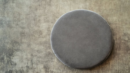 A simple round gray cushion rests on a textured background, perfect for enhancing modern interior aesthetics and providing comfort in stylish living spaces.の素材