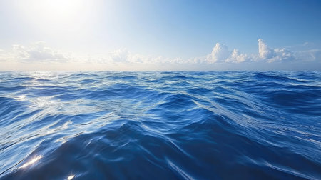 Serene view of ocean waves gently rolling under a bright blue sky scattered with soft clouds, capturing the essence of nature's calm and beauty in tranquil waters.の素材