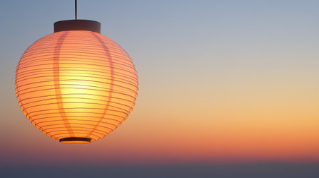 A serene paper lantern emits a gentle glow as it hangs against a breathtaking sunset, showcasing vibrant colors blending seamlessly in the evening sky.の素材