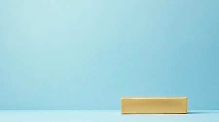 A minimalistic gold box rests elegantly on a soft blue background, creating a modern and clean visual. Perfect for design inspirations or product showcases.の素材