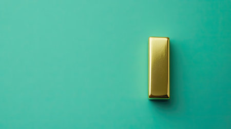 A captivating gold bar rests on a teal background, showcasing a minimalist aesthetic. The smooth surface reflects light, emphasizing luxury and wealth.の素材
