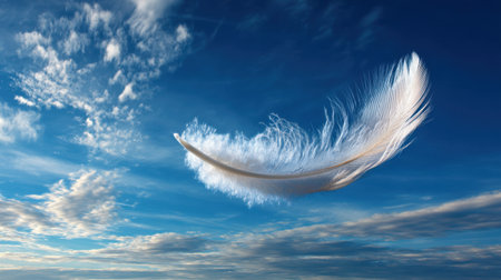 A delicate white feather gracefully drifts through a bright blue sky adorned with wispy clouds, evoking feelings of tranquility, peace, and artistic inspiration in nature.の素材