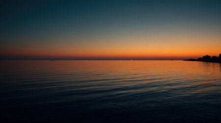 This breathtaking image captures the serene beauty of twilight over calm waters, showcasing a stunning sunset with vibrant hues reflected on the peaceful surface.の素材