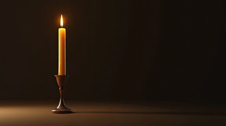 A single yellow candle stands in a vintage holder, casting a soft glow against a dark background. The warm light creates a peaceful ambiance, perfect for relaxation and meditation.の素材