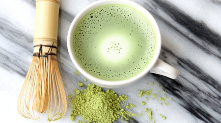 Discover a serene matcha tea moment with a bowl of smooth green drink, accompanied by a bamboo whisk and fresh powder on a marble surface. Ideal for wellness.の素材