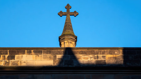 A striking cross atop a stone spire silhouetted against a vibrant blue sky, capturing a moment of tranquility and spirituality in a historical setting.の素材