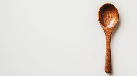 A beautifully crafted wooden cooking spoon stands isolated on a light background, showcasing its unique grain and texture, perfect for culinary artistry.の素材