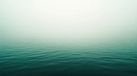 This image captures a serene and minimalist view of calm water enveloped in a soft mist, creating a tranquil atmosphere and inviting reflection.の素材