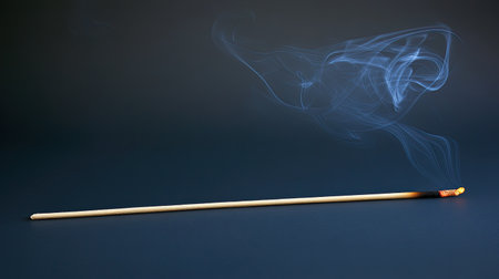 A serene image capturing the graceful smoke trails from a burning incense stick, evoking themes of tranquility, relaxation, and sensory indulgence in a minimalist setting.の素材