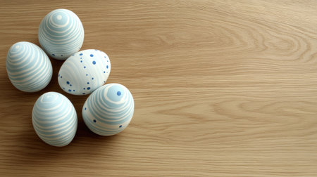 This image features a collection of decorative Easter eggs in soft pastel colors arranged on a light wooden surface, creating a warm and inviting atmosphere for spring celebrations.の素材