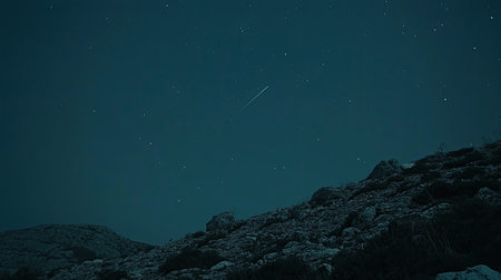 A captivating view of a dark night sky filled with stars, featuring a bright shooting star above a rugged rocky landscape. Perfect for astronomy enthusiasts.の素材