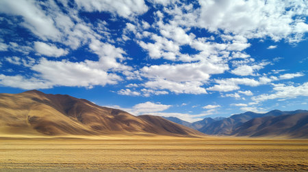 Expansive desert landscape featuring mountains under a vibrant blue sky with fluffy clouds. A serene and picturesque view showcasing the beauty of nature.の素材