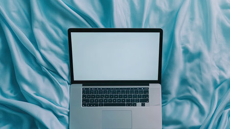 Blank laptop screen on a soft blue fabric surface, creating a calm and serene environmentの素材