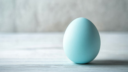 A single pastel-colored Easter egg resting on a white wooden table with plenty of copy space, minimalistic style, soft natural lighting, and a clean background.の素材