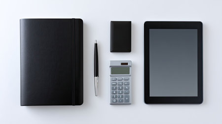 A clean and minimal workspace arrangement featuring a black notebook, pen, calculator, tablet, and other essentials, ideal for productivity and organization.の素材