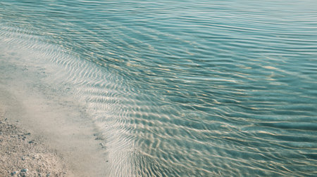A serene view of a sandy beach where gentle waves meet the water's edge, creating a tranquil atmosphere perfect for relaxation and escape into nature's beauty.の素材