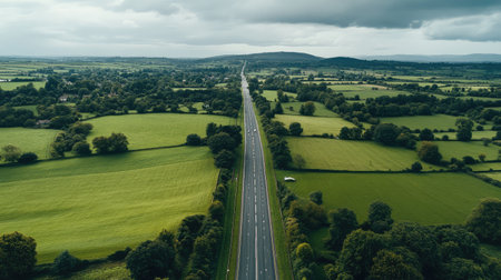 An aerial view of a long stretch of highway running through the countryside, with green fields and trees visible, providing space for copy.の素材