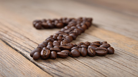 Alphabet A to Z spelled with coffee beans on wooden table, warm brown tones with clean spaceの素材
