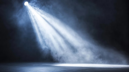 Bright concert spotlight cutting through a smoky haze, with light rays glowing in the darkness, highlighting the empty space. No text, no people.の素材