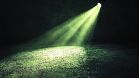 Green spotlight shining across a dark floor, casting elongated shadows with the light gradually fading into the surrounding darkness. No text, no people.の素材