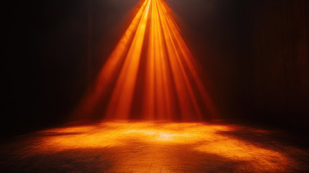 Orange spotlight on a dark stage floor, with soft rays radiating outward and the edges blurred for a soft, romantic effect. No text, no people.の素材