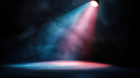 A vibrant concert spotlight focused on a dark stage, creating a bright beam of light that softly fades at the edges into surrounding shadows. No text, no people.の素材