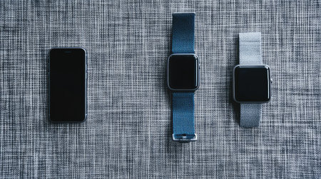 Flat lay of phone and smartwatch on gray fabric surface, top view of wearable and mobile tech with clean copy spaceの素材