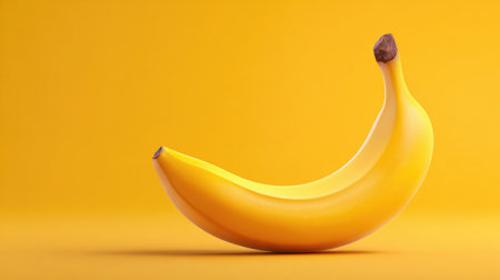 A single bright yellow banana rests against a smooth yellow background, highlighting its natural texture and color, ideal for food-related themes and healthy lifestyle concepts.の素材