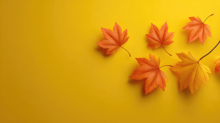 A beautiful arrangement of autumn leaves in shades of orange and yellow against a vibrant yellow background, perfect for capturing the essence of fall in design and decoration.の素材