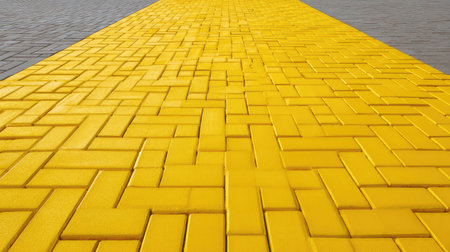 A vibrant yellow brick pathway featuring a unique pattern stretches through an urban environment, offering a striking visual element in outdoor public spaces.の素材