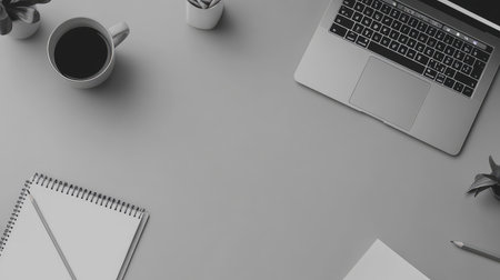 Clean workspace with an open laptop, empty notepad, and pencil on a light grey desk with center copy space for communication conceptの素材