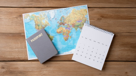 Travel service layout with map, passport, ticket, and calendar on wooden surface, white area left blankの素材