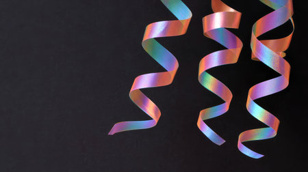 Metallic streamers and party decor on black backdrop with copy spaceの素材