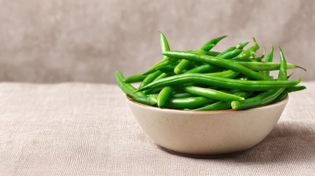 A bowl of green beans placed in the corner of a textured linen background with generous copy spaceの素材