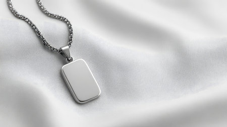 A sleek silver pendant rests on elegant smooth fabric, showcasing minimalism and luxury in a radiant light. Ideal for jewelry displays and fashion concepts.の素材
