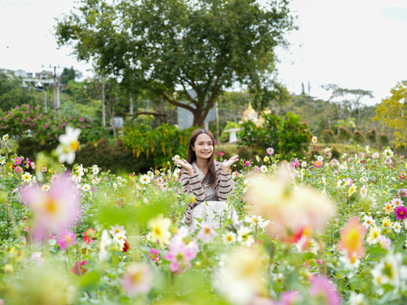 Young woman enjoys vibrant flower field, surrounded by colorful blooms. She smiles joyfully, embodying sense of happiness and tranquility in nature beautyの写真素材