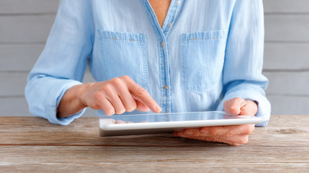 A woman engages with a tablet device on a rustic wooden table, showcasing a relaxed lifestyle intertwined with modern technology and connectivity.の素材