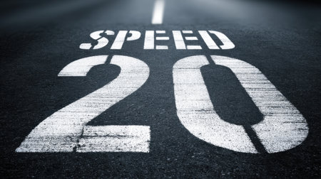 A striking image featuring a speed limit sign displaying the number twenty on a dark asphalt road, capturing a sense of urban movement and safety.の素材