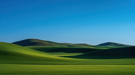 Captivating landscape featuring rolling green hills under a clear blue sky, showcasing the beauty and tranquility of nature with smooth curves and soft shadows.の素材