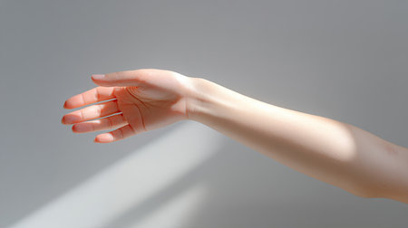 This image features an elegant hand reaching outward, interacting with soft light and shadows against a minimal background, embodying beauty and tranquility.の素材