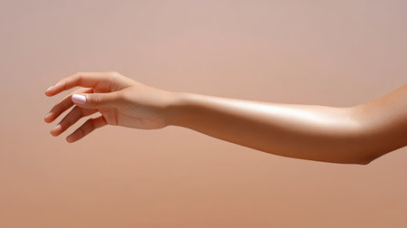 A stunning close-up of a graceful arm with smooth skin reaching out against a soft gradient background, ideal for beauty and wellness themes.の素材