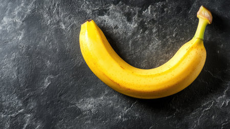 A ripe, bright banana placed on a clean surface with the curve forming a natural smile, with empty space on the side for branding or textの素材