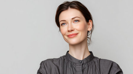 A portrait of a confident young woman with a warm smile, expressive eyes, and a casual yet elegant style, set against a neutral gray background, radiating positivity and self-assurance.の素材