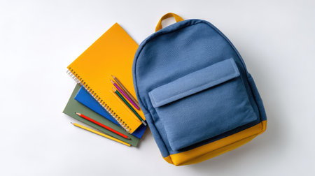 A vibrant blue backpack with a yellow bottom sits alongside colorful notebooks and pencils, perfect for students preparing for a new school year or artistic projects.の素材
