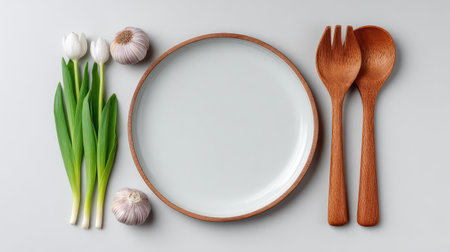 A beautiful arrangement featuring fresh tulips, garlic, and minimalist wooden cutlery on a pale background, ideal for celebrating culinary arts and inviting meal experiences.の素材