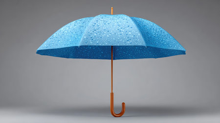 A vibrant blue umbrella adorned with raindrops, elegantly displayed against a neutral grey background, perfect for illustrating weather themes and rainy day imagery.の素材