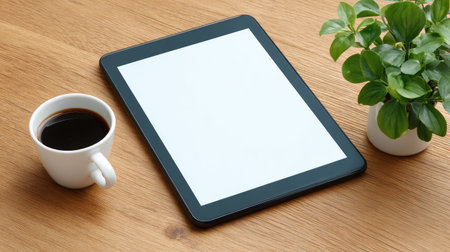 A stylish tablet rests on a wooden surface next to a cup of coffee and a fresh green plant, perfect for creating a calming atmosphere for work or leisure activities.の素材