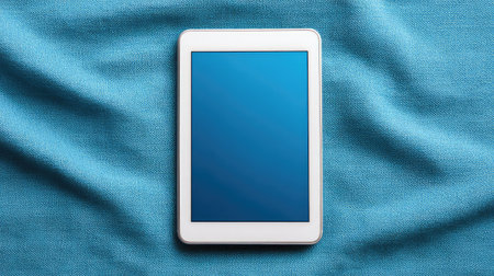 A sleek tablet sits on soft blue fabric, featuring a blank screen perfect for displaying apps, designs, or media. Ideal for technology themes and workspace concepts.の素材